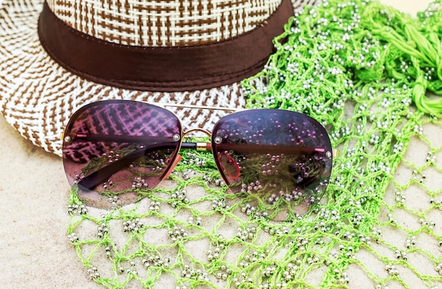 Sunglasses with hat and pareo on the sand