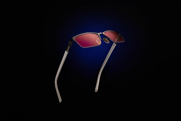 Sunglasses with pink lenses on a blackblue background