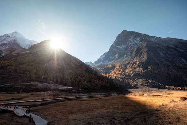 Sunlight on mountain with tourists trekking on meadow at Yading