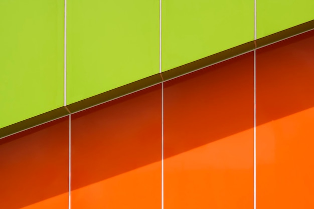 Sunlight and shadow on green and orange aluminum composite tile wall outside of modern building