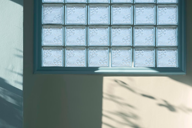 Sunlight and shadow on surface of glass brick block on white and blue concrete wall inside of home
