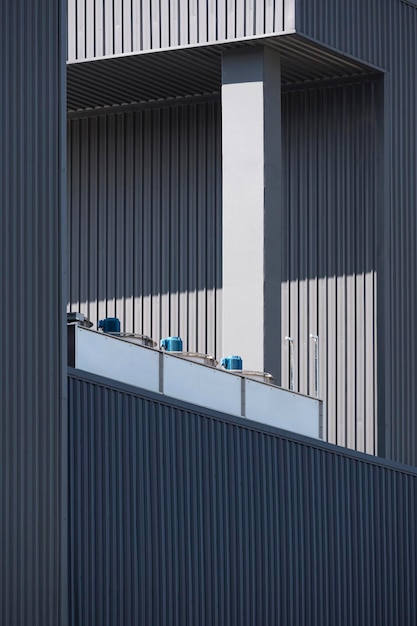 Sunlight and shadow on surface of heat conditioner compressors on top of black industrial building