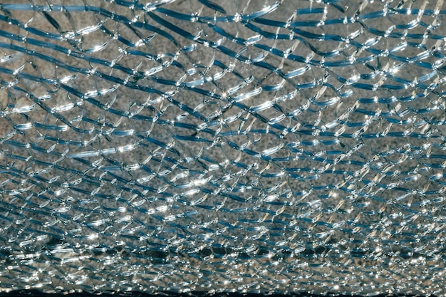 Sunlight shimmers through cracked glass pattern on window in closeup view revealing shattered detail