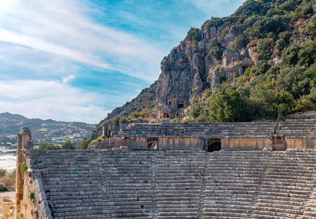 Sunlit ruins of antique amphitheater against the backdrop of the famous rocky necropolis in Myra (now Demre, Turkey)