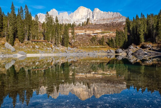 Sunny colorful autumn alpine Dolomites mountain scene Sudtirol Italy Karersee or Lago di Carezza view