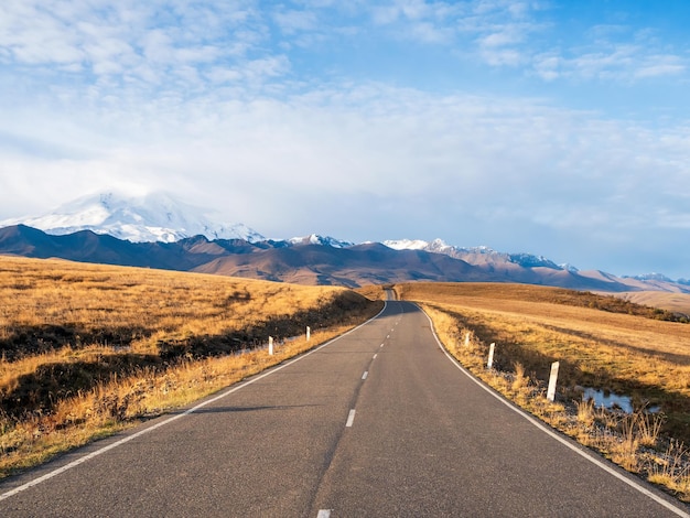 Sunny highway to the snowcapped peaks Autumn morning deserted highway Beautiful asphalt freeway motorway highway through of caucasian landscape mountains hills