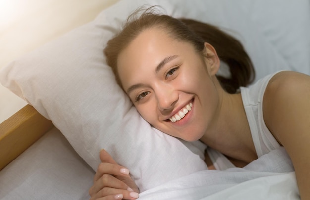 Sunny morning Happy woman waking up lying in bed