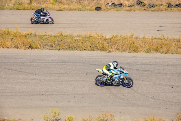 Sunny summer day. A straight section of the old highway. Two motorcyclists compete in speed on sports bikes