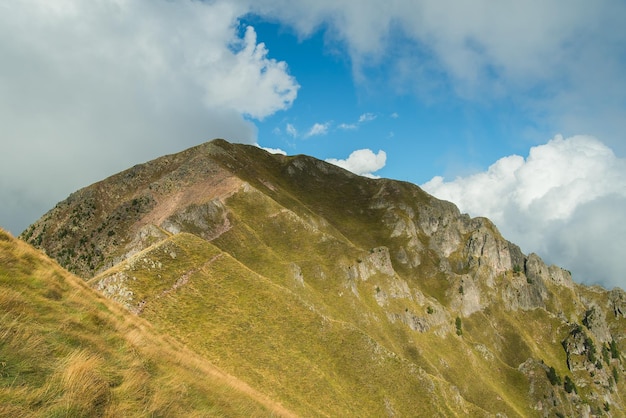 Sunny valley among majestic green cloudy mountain hills covered in green lush grass and bushes