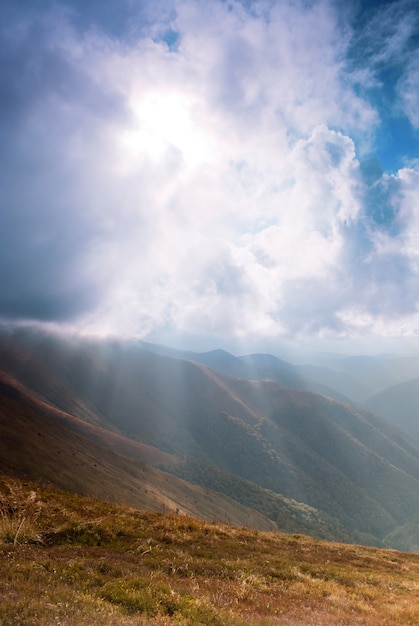 Sunrays through the clouds on the sky in mountains range