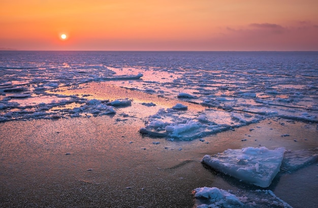 Sunrise and frozen sea Beautiful winter landscape with lake and red sun in morning time Daybreak