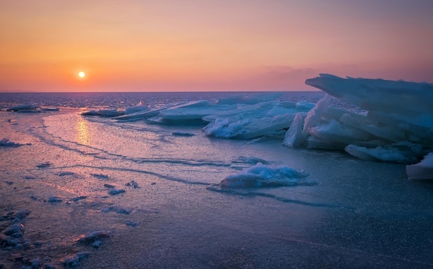 Sunrise and frozen sea Beautiful winter landscape with lake and red sun in morning time Daybreak