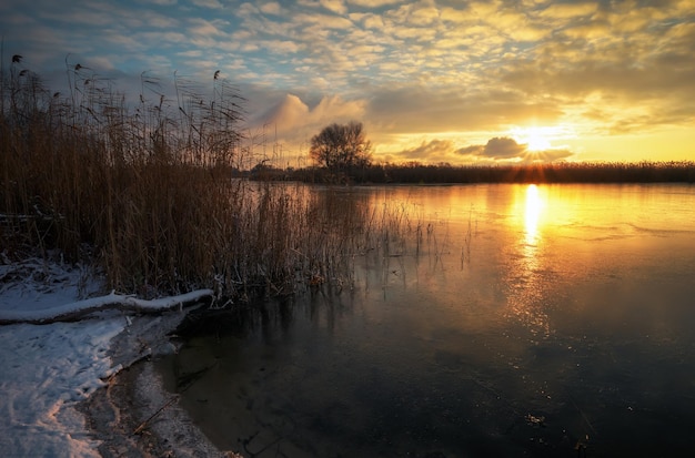 Sunrise and frozen sea. Beautiful winter landscape with lake in sunset time.