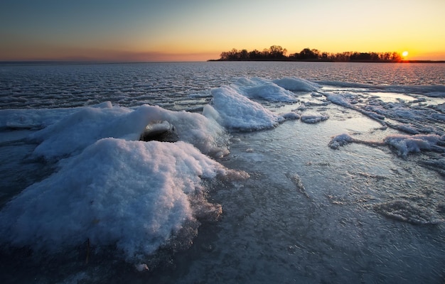 Sunrise and frozen sea coast Beautiful winter landscape with lake in morning time