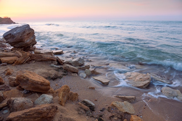 Sunrise landscape the rocky sea coast and water waves