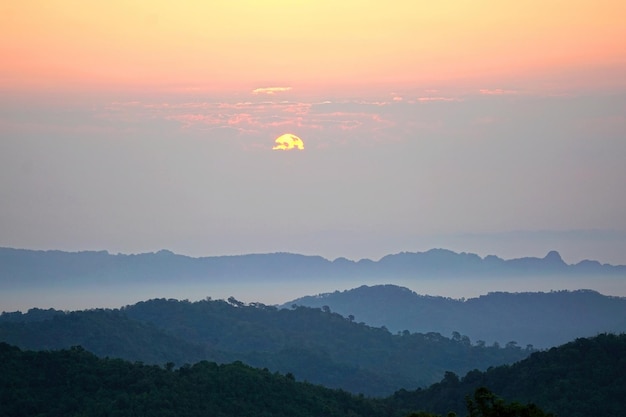 Sunrise over layers of mountain view in morning fog with colorful twilight sky at Noen Chang Suek, Pilok, Kanchanaburi, Thailand.