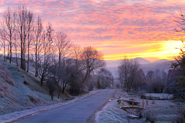 Sunrise and mountain village road with first autumn frosts