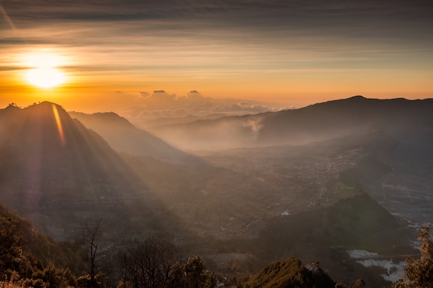 Sunrise over mountain with fog with village on hill at morning