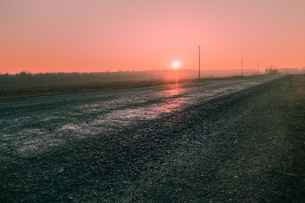 Sunrise in the pink sky in the early morning on a country road. The morning sun rises above the horizon in the early morning on a new day.