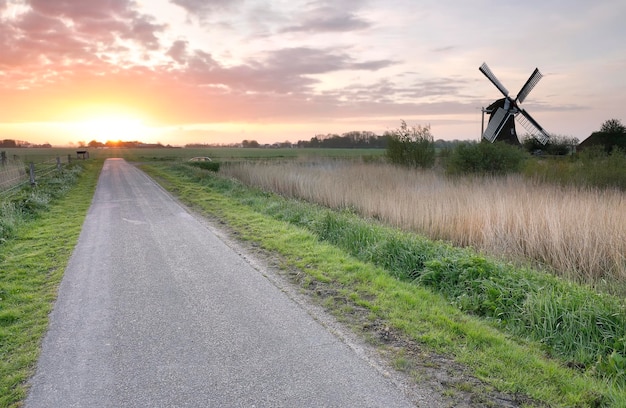 Photo sunrise over rural road and windmill