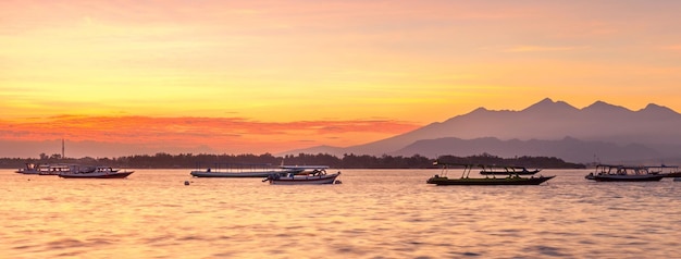 Sunrise over a sea bay with boats with mountains on the horizon Bali Indonesia Golden sunset