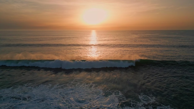 Sunrise sea surf washing beach drone view golden dawn sky ocean water surface