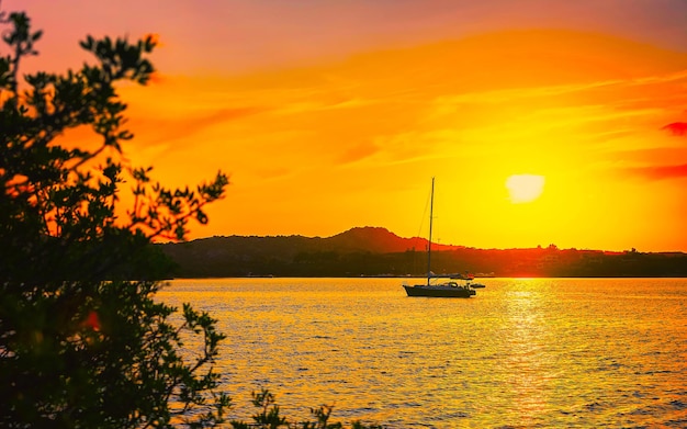 Sunrise or sunset with yachts at Porto Rotondo on Costa Smeralda at Mediterranean sea in Sardinia island of Italy. Boat in Sardegna in summer. Landscape of Olbia province. Mixed media.