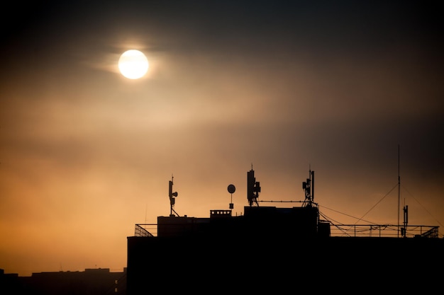 Sunrise with silhouettes of communication antenna with a dishes on the roof