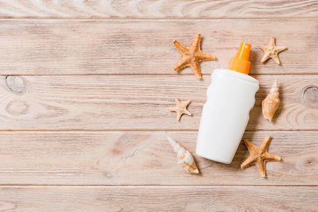 Photo sunscreen bottles with seashells and starfish on wooden table with copy space. flat lay concept of summer travel vacation.