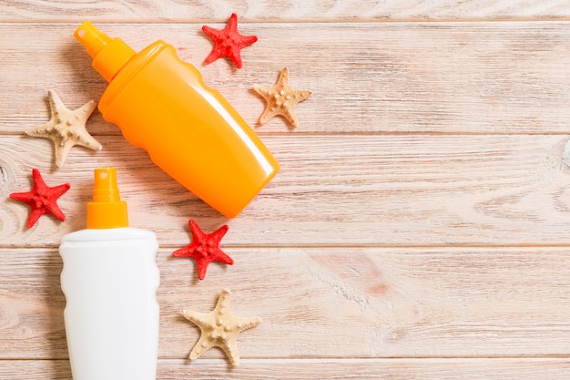 Photo sunscreen bottles with seashells and starfish on wooden table with copy space. flat lay concept of summer travel vacation