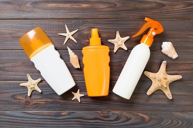 Photo sunscreen bottles with seashells on white wooden table. travel healthcare accessories top view.