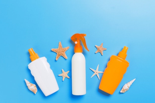 Sunscreen cream with starfish and seashells in bottles, top view