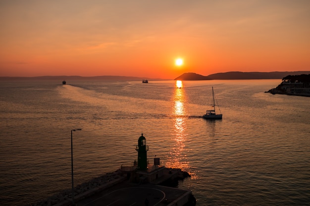 Sunset over the Adriatic Sea and its boats playing in the reflections at the entrance to the port of Split in Croatia.