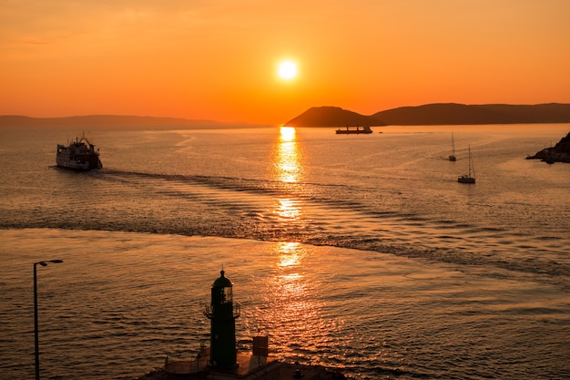 Sunset over the Adriatic Sea and its boats playing in the reflections at the entrance to the port of Split in Croatia.