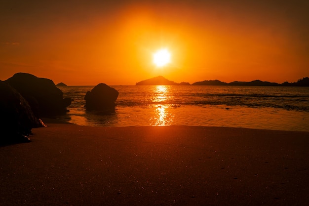 Sunset at beach with orange sky and rocks