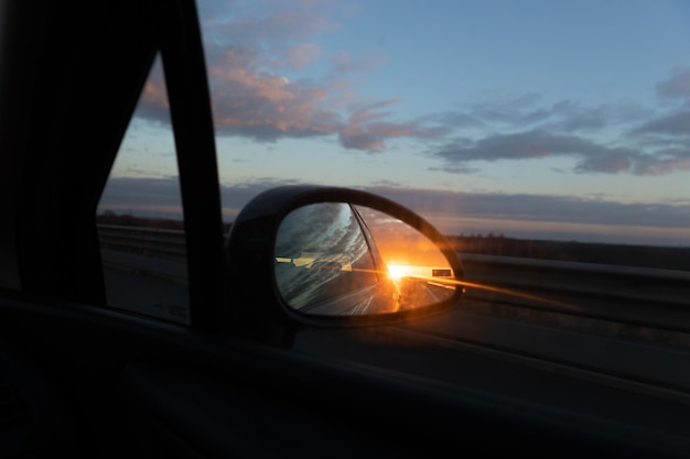 Sunset in the car mirrorConcept of travelling by car