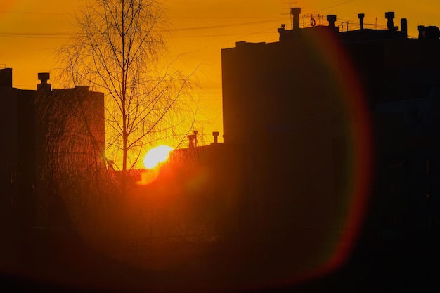 Sunset in city between multistorey buildings Silhouette of houses against backdrop of sunset Atmospheric background