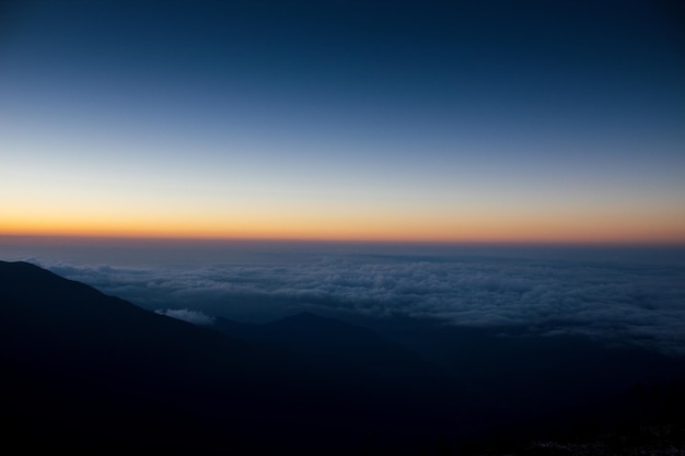 A sunset over the clouds with the sun setting behind it