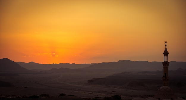 Sunset over desert with muslim mosque in the foreground