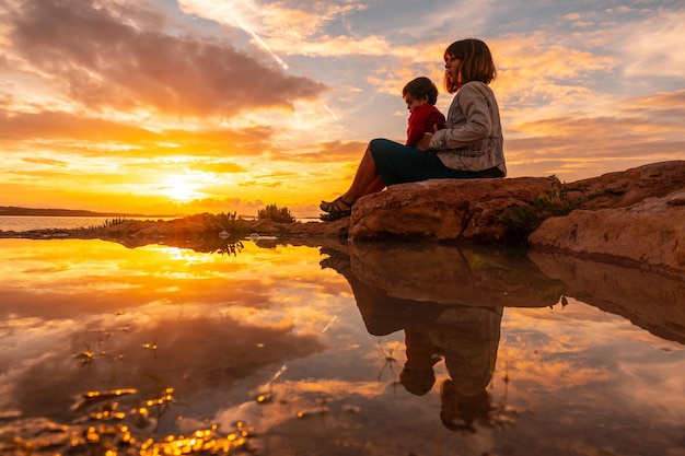 Sunset in Ibiza on vacation a mother with her son sitting by the sea in San Antonio Abad