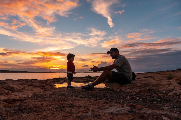 Sunset in Ibiza on vacation young father with his son having fun by the sea in San Antonio Abad