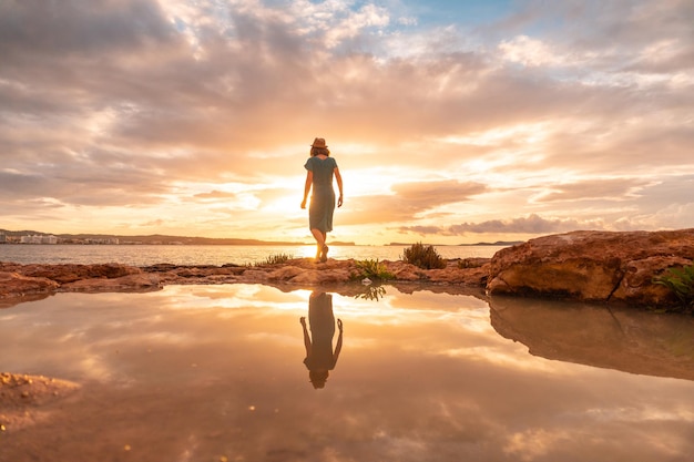 Sunset in Ibiza on vacation a young tourist with a hat in San Antonio Abad Balearic