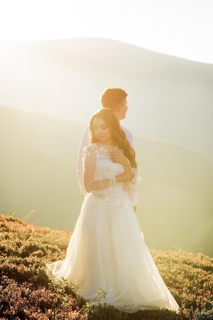 Sunset illuminates mountain hill where wedding couple walks