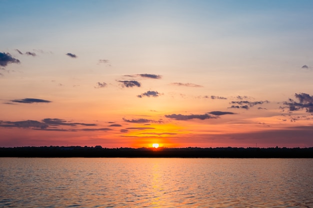 Sunset in the lake. beautiful sunset behind the clouds above the over lake landscape backg