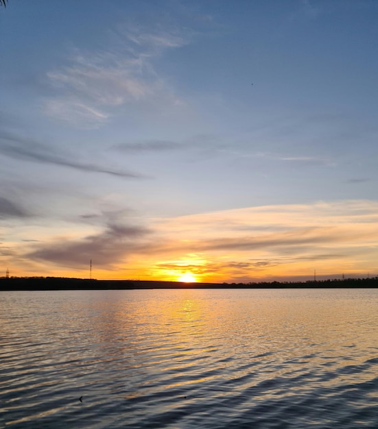 A sunset over a lake with a few clouds in the sky