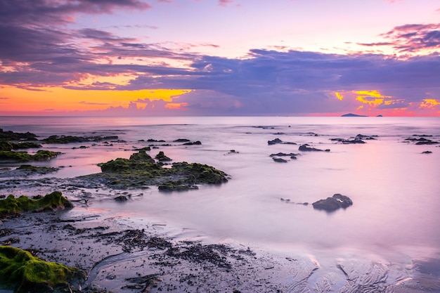 Sunset landscape on the beach rocks in foreground