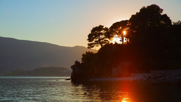 Sunset landscape with silhouettes of trees by the water. Nature of Montenegro, scenic panoramic view