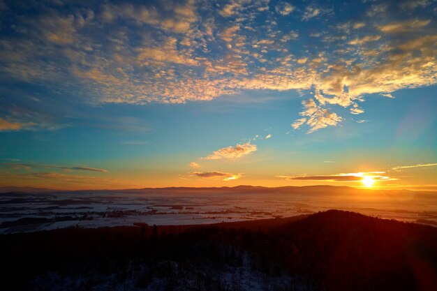 Sunset over mountains with forest covered with snow