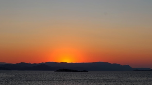 A sunset over the mountains with the sun setting behind it