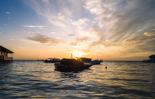 A sunset over the ocean with boats in the foreground and the sun setting behind it